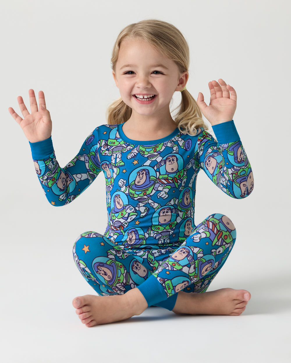 Sitting girl wearing the Disney & Pixar Buzz's Cosmic Crew Two-Piece Pajama Set