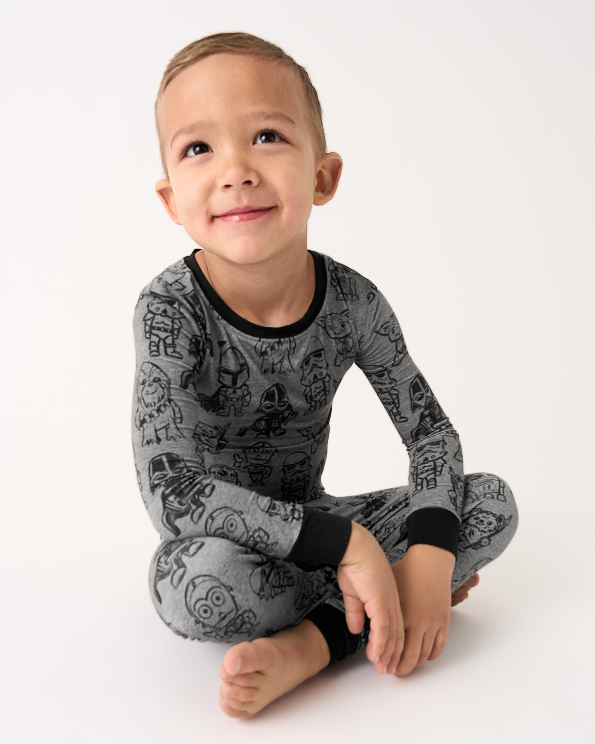 Sitting boy wearing the Star Wars Far, Far, Away Friends Two-Piece Pajama Set