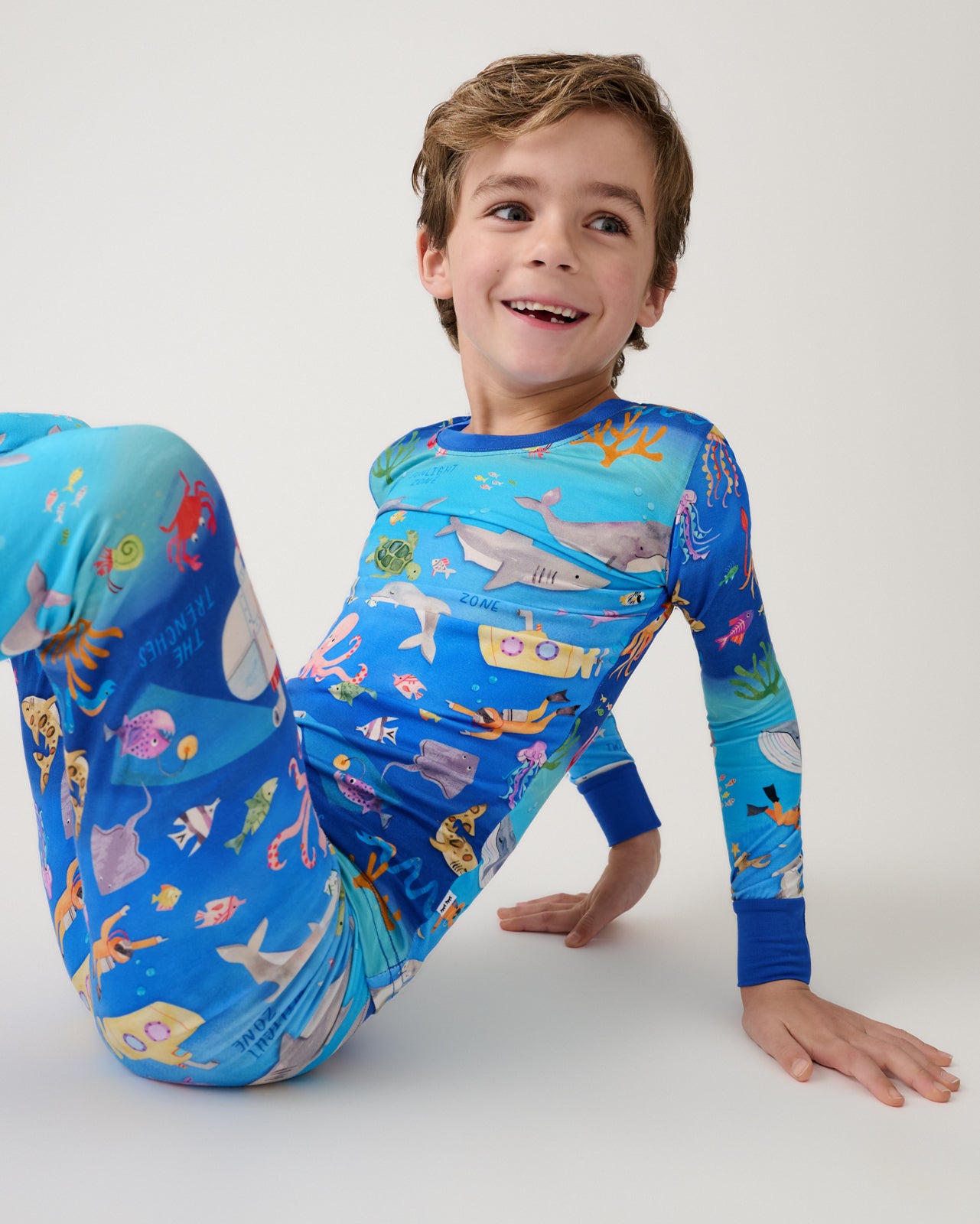 Sitting boy wearing the Underwater Discovery Two-Piece Pajama Set