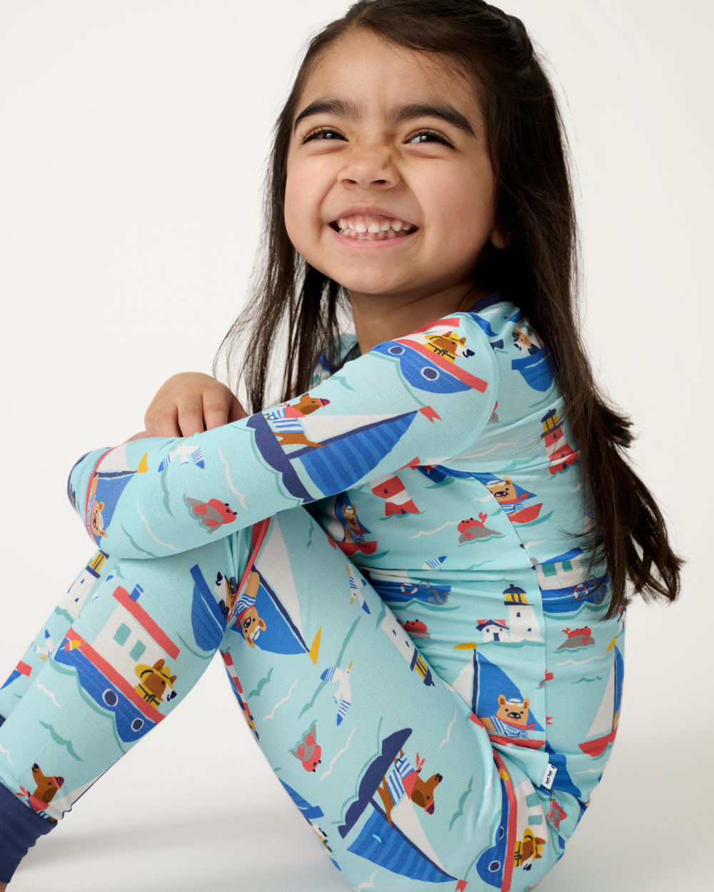 Sitting girl wearing the Nautical Paws Two-Piece Pajama Set