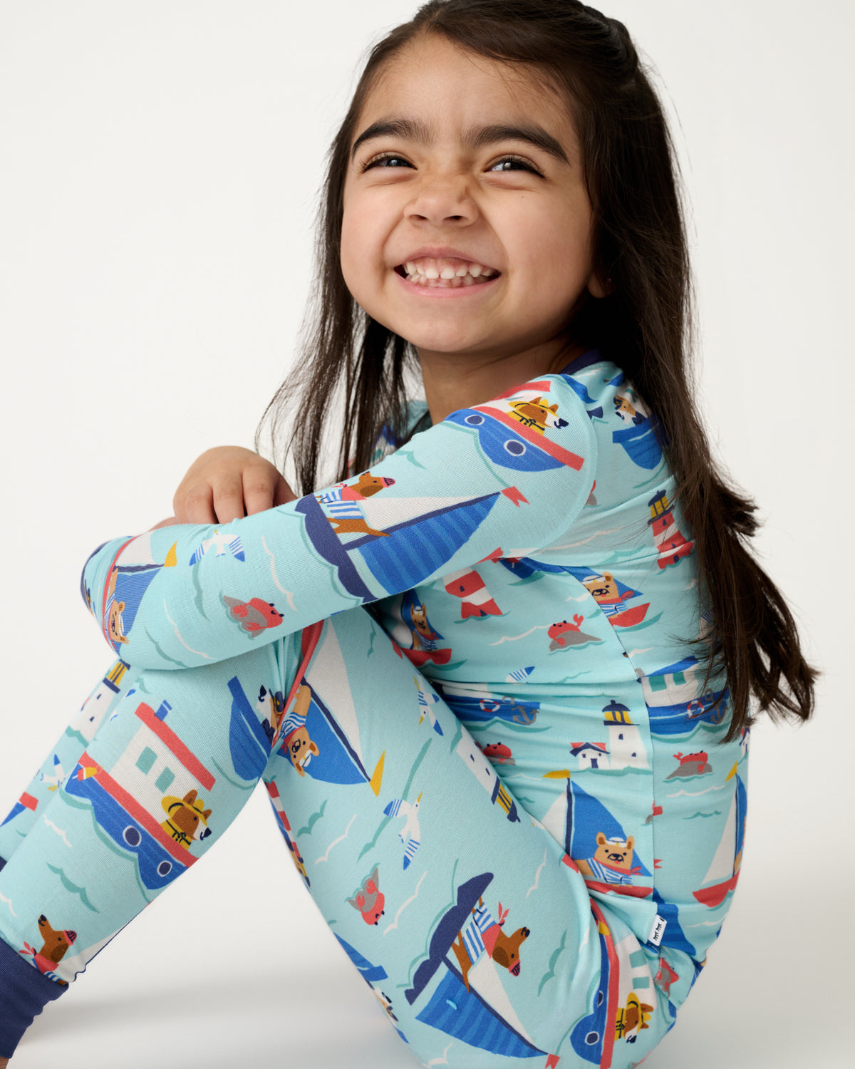 Sitting girl wearing the Nautical Paws Two-Piece Pajama Set
