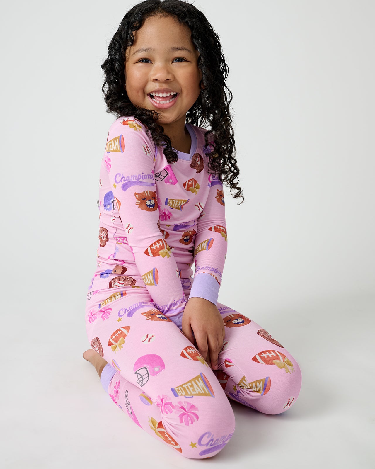 Sitting child wearing the Team Spirit Pink Two-Piece Pajama Set