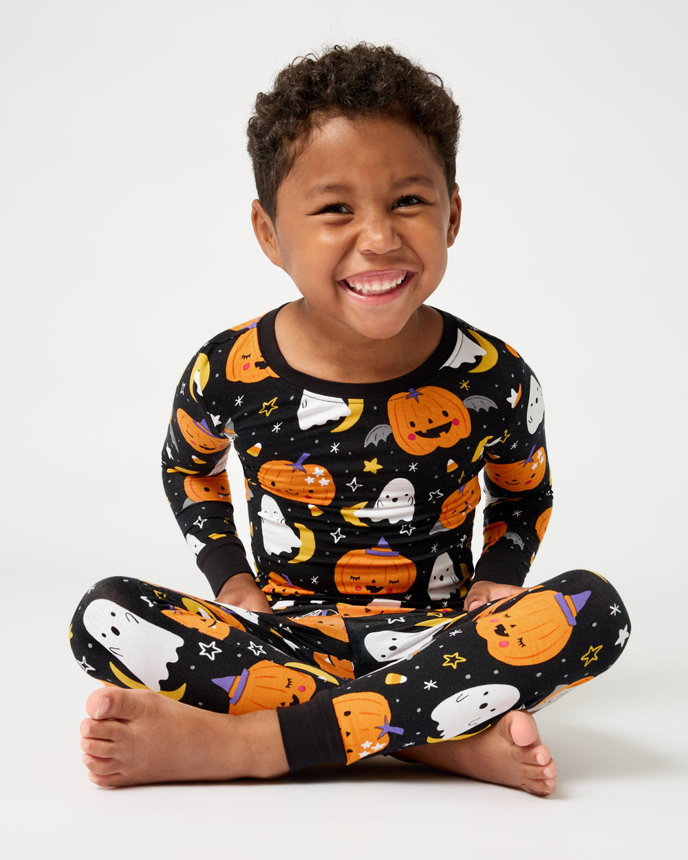 Sitting boy wearing the Moonlit Magic Two-Piece Pajama Set