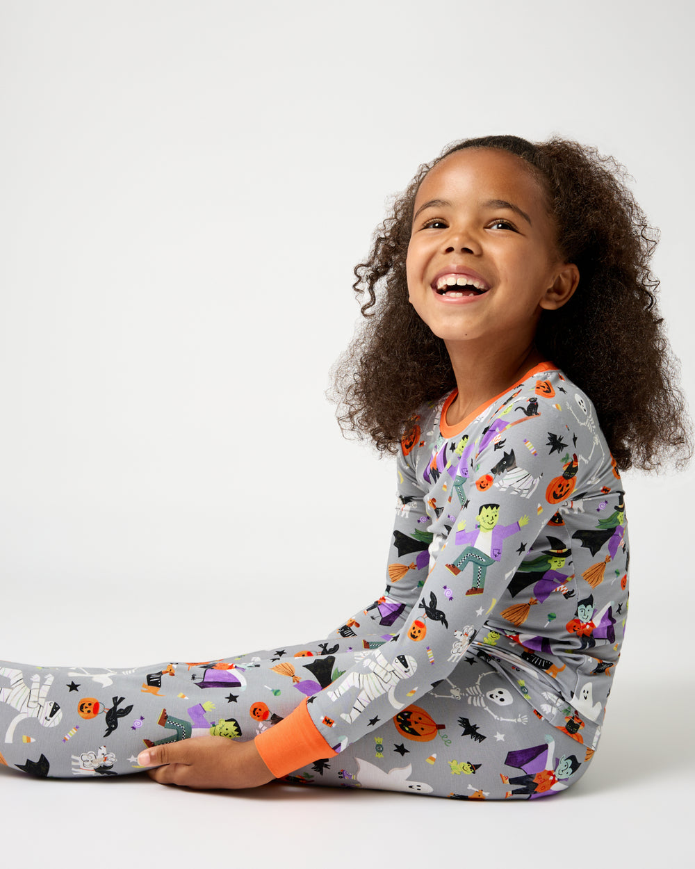 Sitting child wearing the Dracula's Disco Halloween Two-Piece Pajama Set