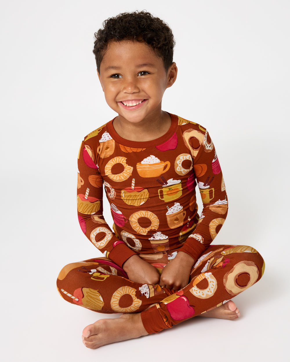 Sitting boy wearing the Harvest Sweets Two-Piece Pajama Set