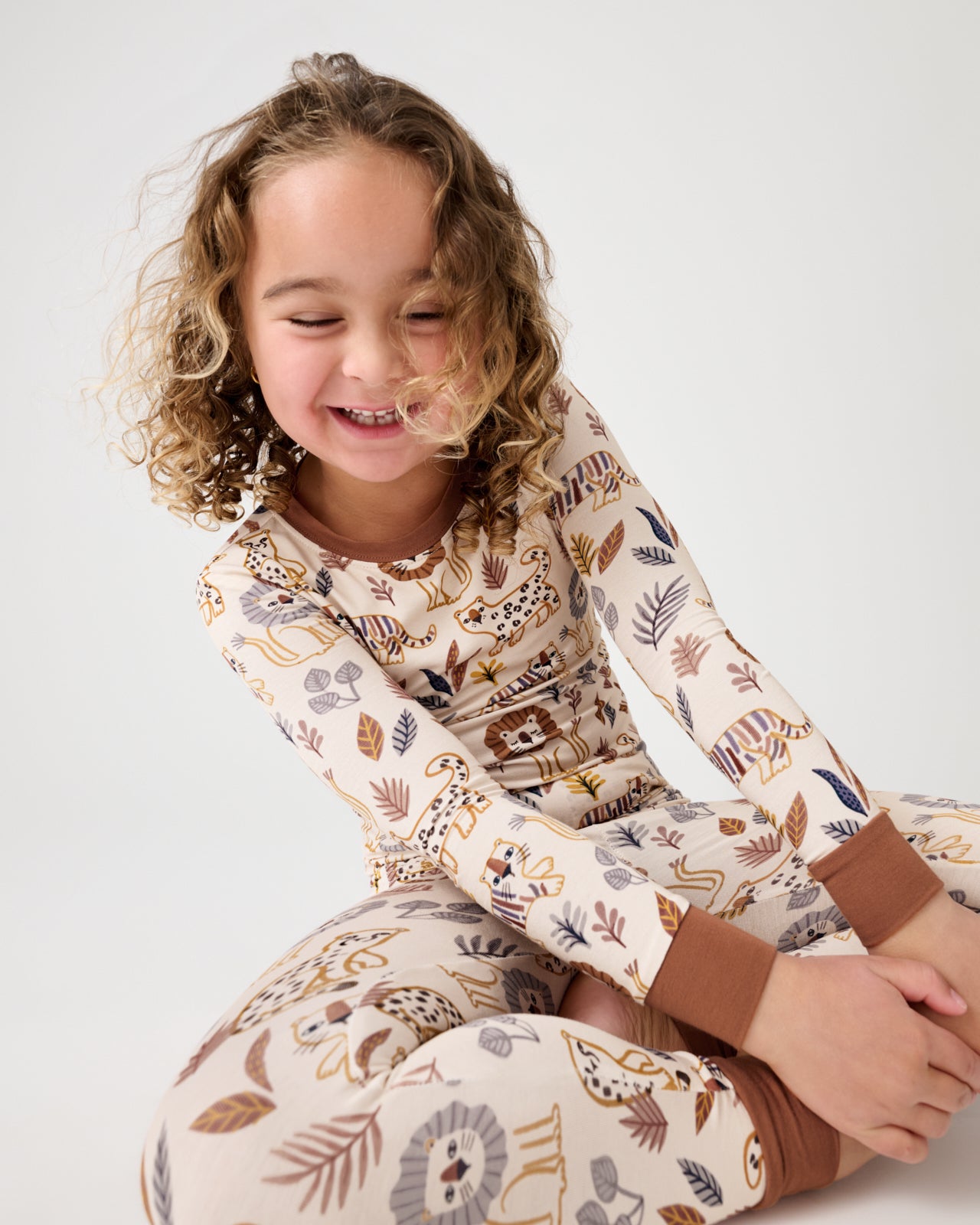 Sitting girl wearing the Savanna Friends Two-Piece Pajama Set