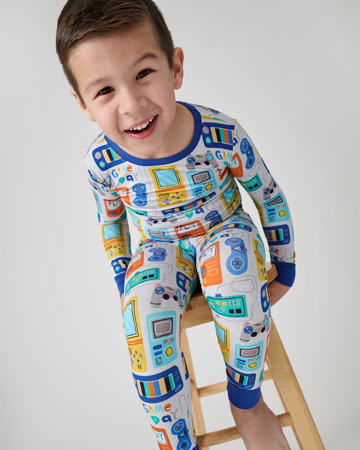 Child sitting on a stool wearing the Game On Two-Piece Pajama Set