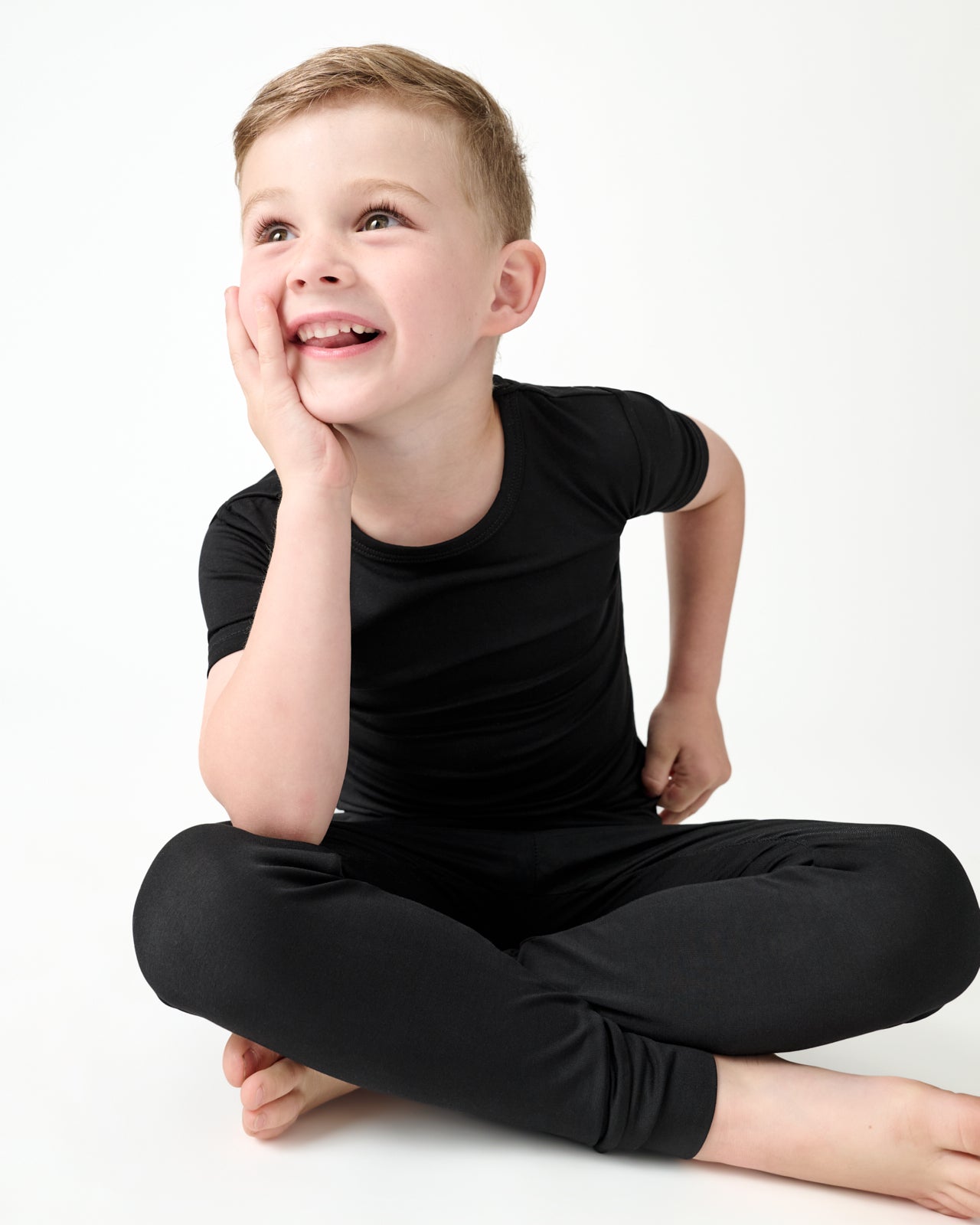 Sitting boy wearing the Black Two-Piece Short Sleeve Pajama Set