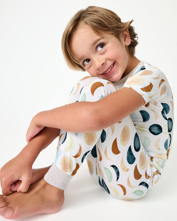 Sitting boy wearing the Luna Neutral Two-Piece Short Sleeve Pajama Set