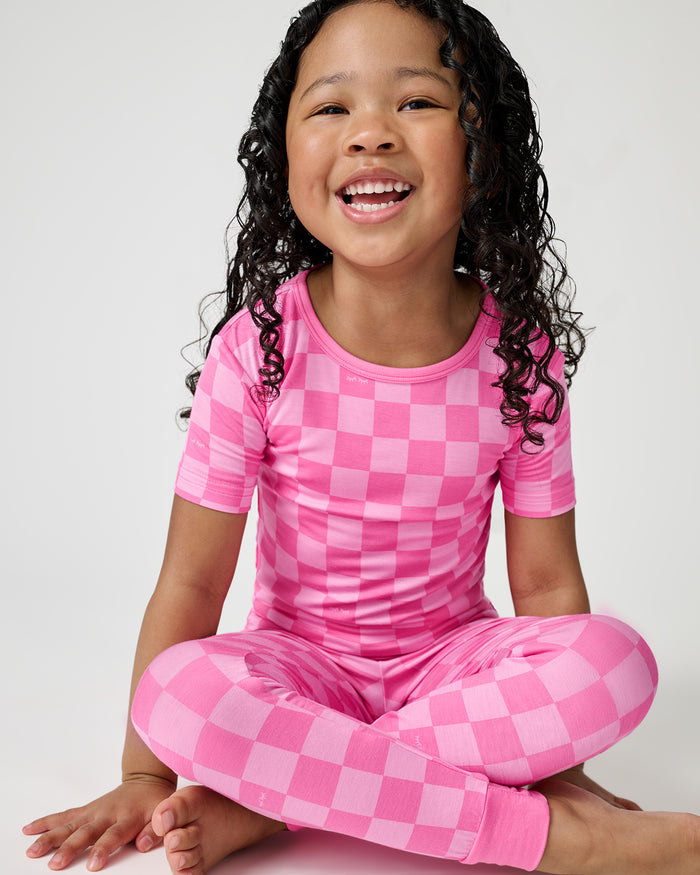Sitting girl wearing the Sweet Raspberry Checks Two-Piece Short Sleeve Pajama Set