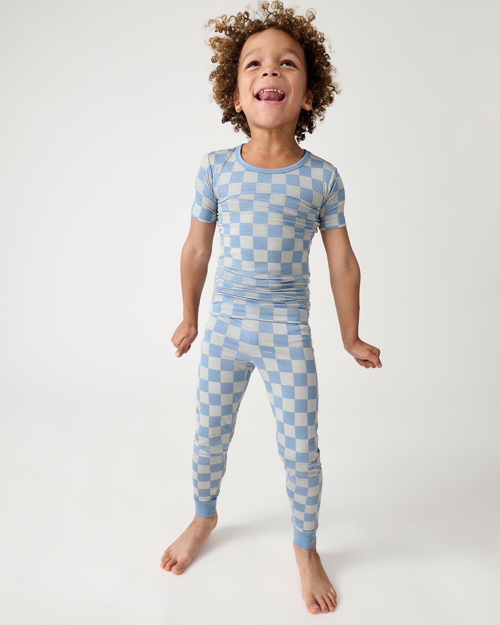Standing child wearing the Dusk Blue Checks Two-Piece Short Sleeve Pajama Set