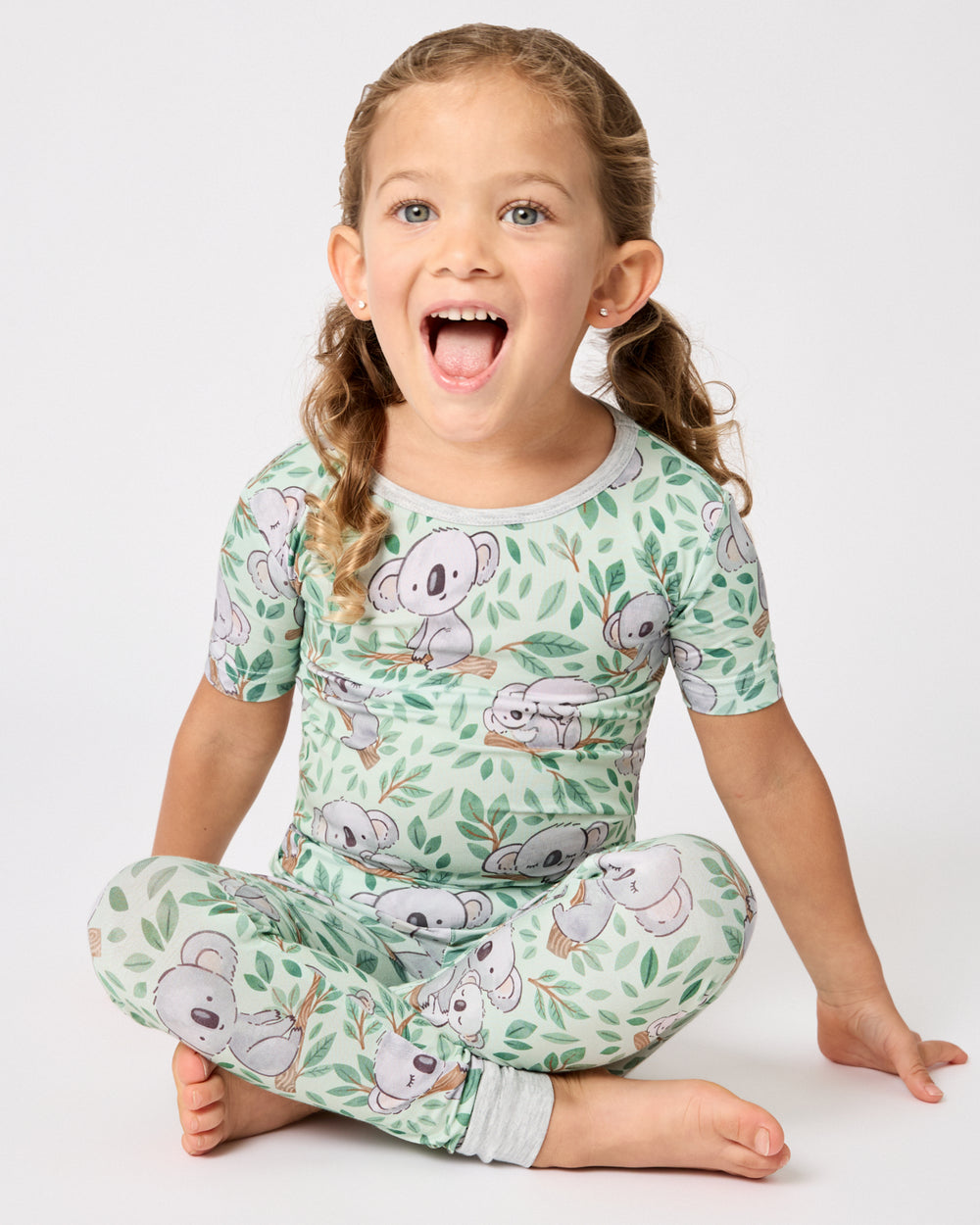Sitting girl wearing the Koala Cuddles Two-Piece Short Sleeve & Pants Pajama Set