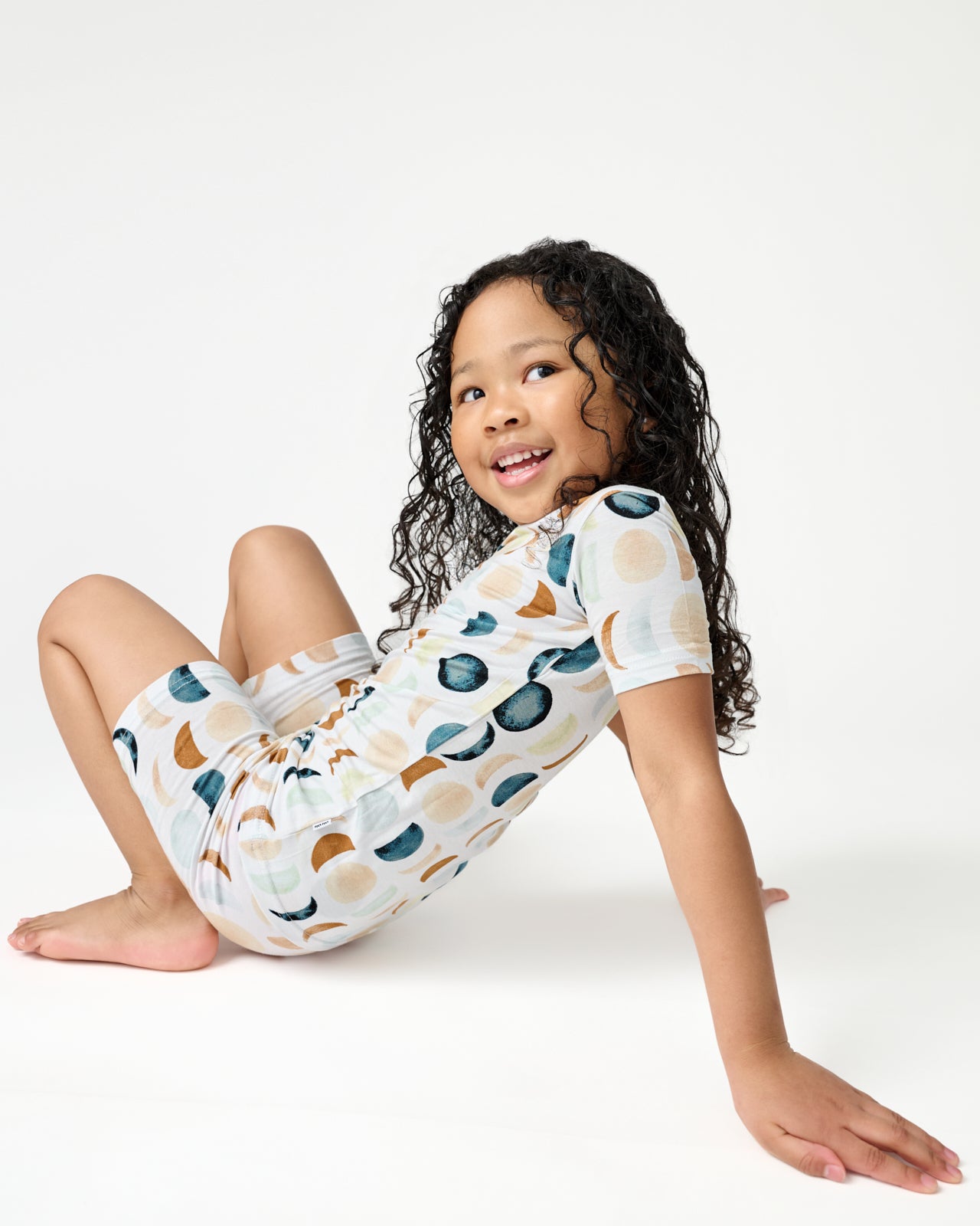 Sitting girl wearing the Luna Neutral Two-Piece Short Sleeve & Shorts Pajama Set