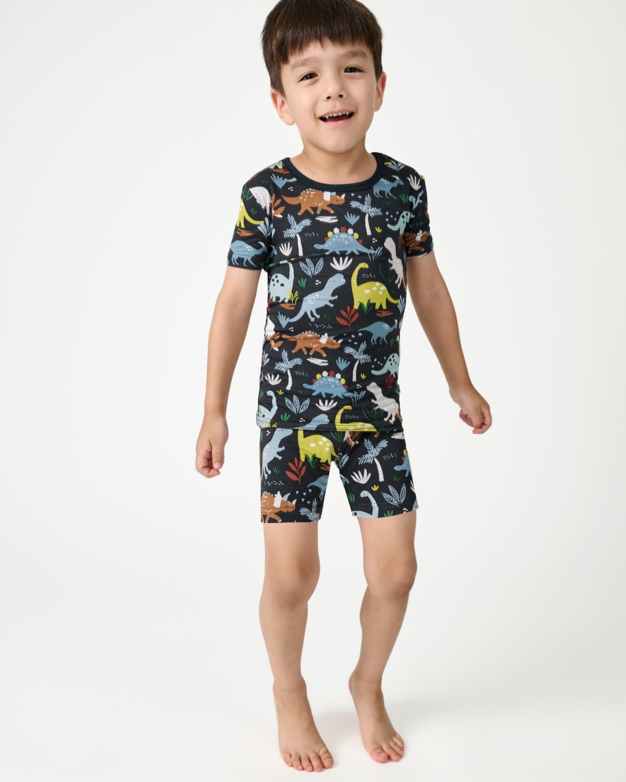 Standing boy wearing the Navy Jurassic Jungle Two-Piece Short Sleeve & Shorts Pajama Set