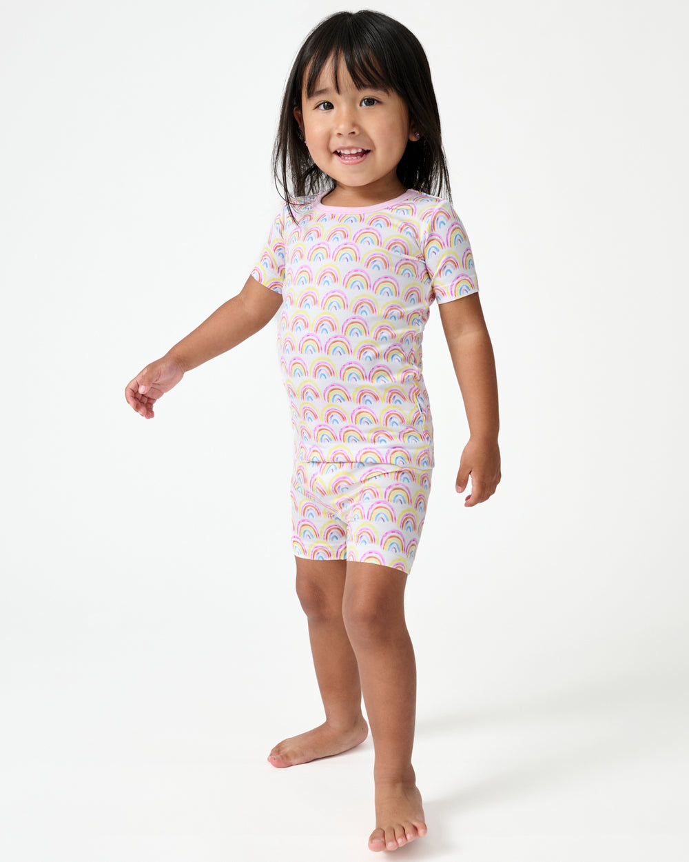 Standing girl wearing the Pastel Rainbows Two-Piece Short Sleeve & Shorts Pajama Set