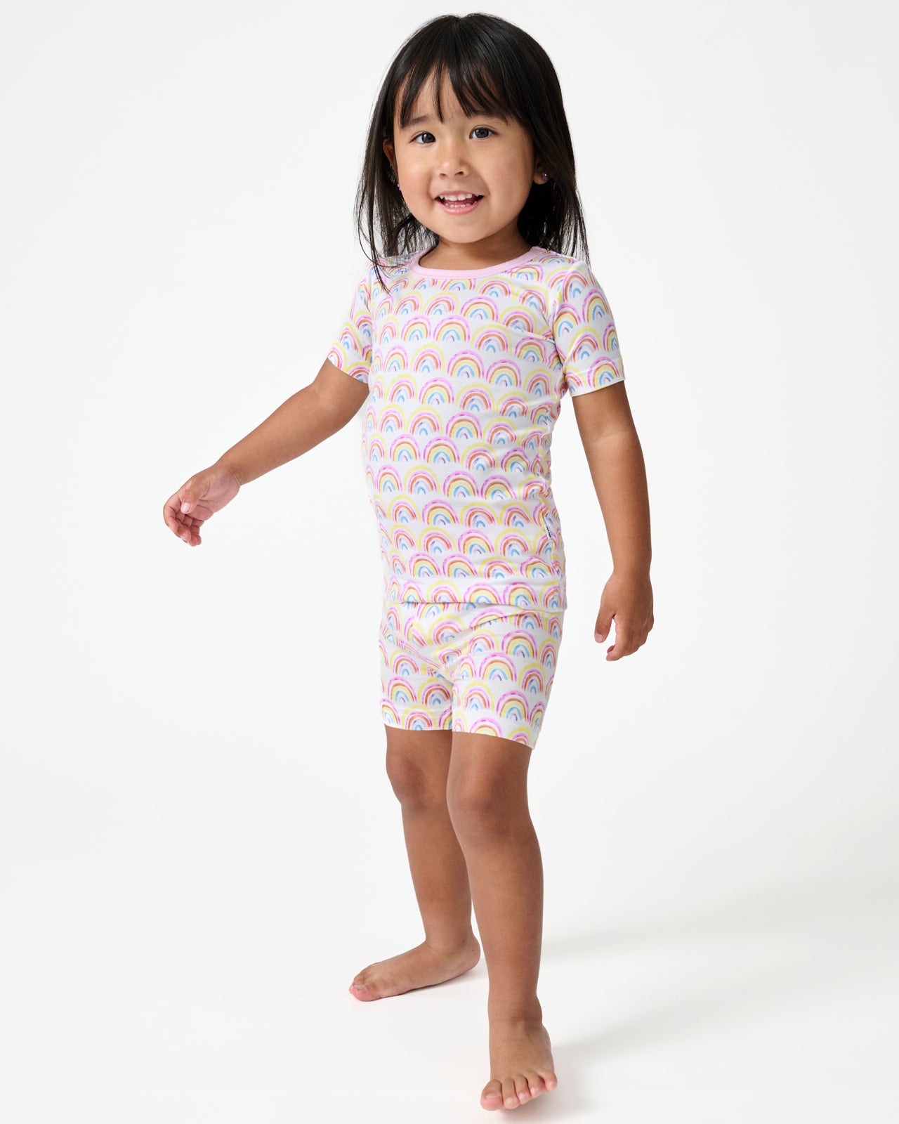 Standing girl wearing the Pastel Rainbows Two-Piece Short Sleeve & Shorts Pajama Set