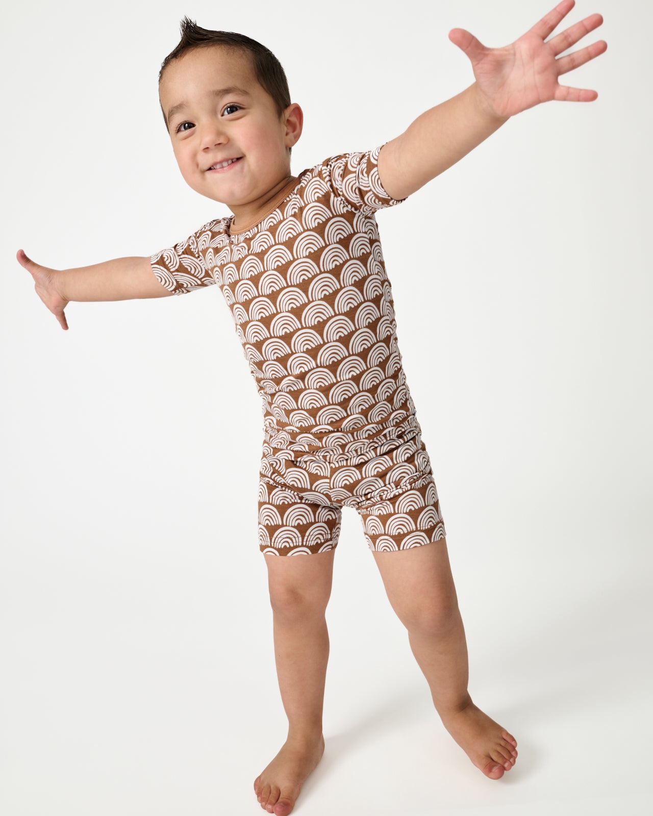 Posing boy wearing the Rust Rainbows Two-Piece Short Sleeve & Shorts Pajama Set