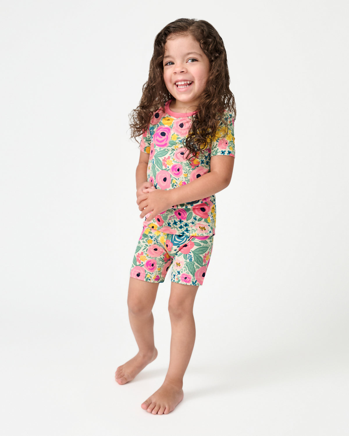 Standing child wearing the Secret Garden Floral Two-Piece Short Sleeve & Shorts Pajama Set