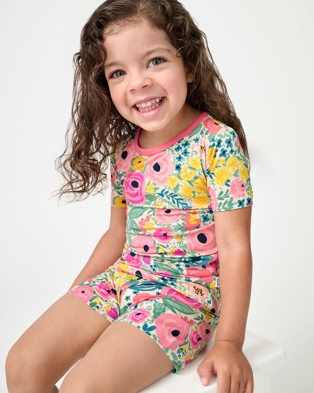 Sitting girl wearing the Secret Garden Two-Piece Short Sleeve & Shorts Pajama Set