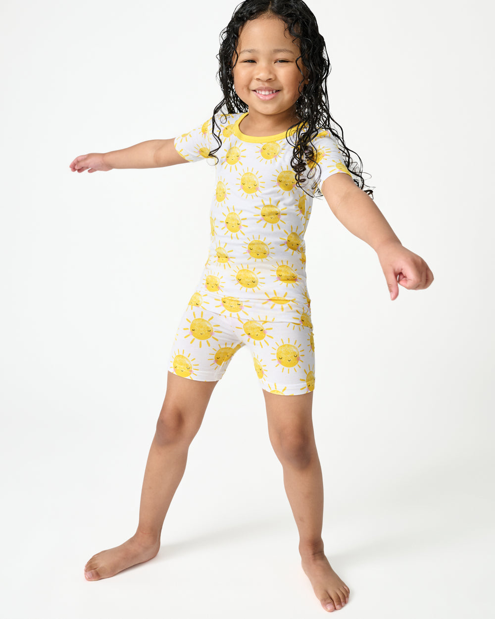 Standing child wearing the Sunshine Two-Piece Short Sleeve & Shorts Pajama Set