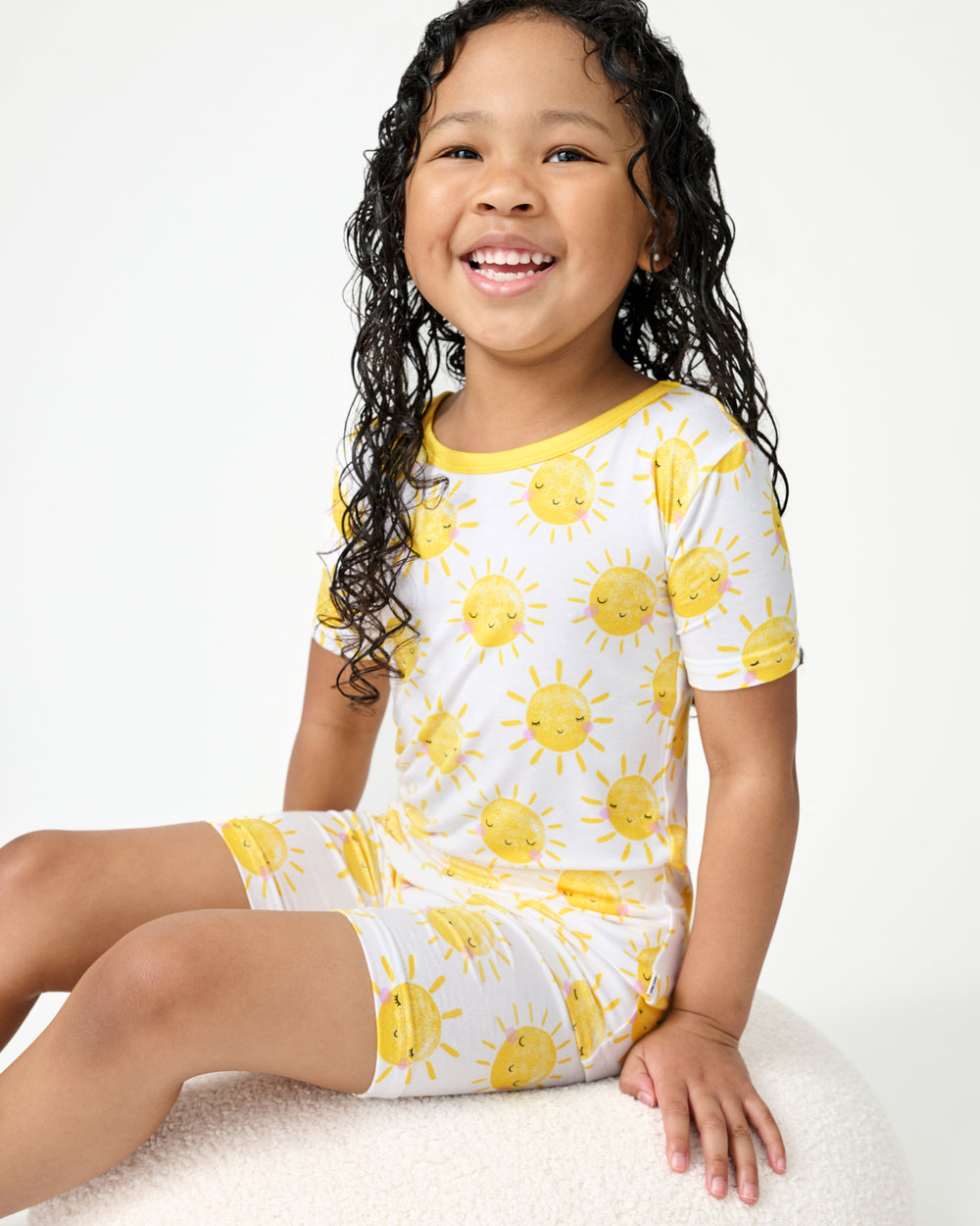 Sitting girl wearing the Sunshine Two-Piece Short Sleeve & Shorts Pajama Set