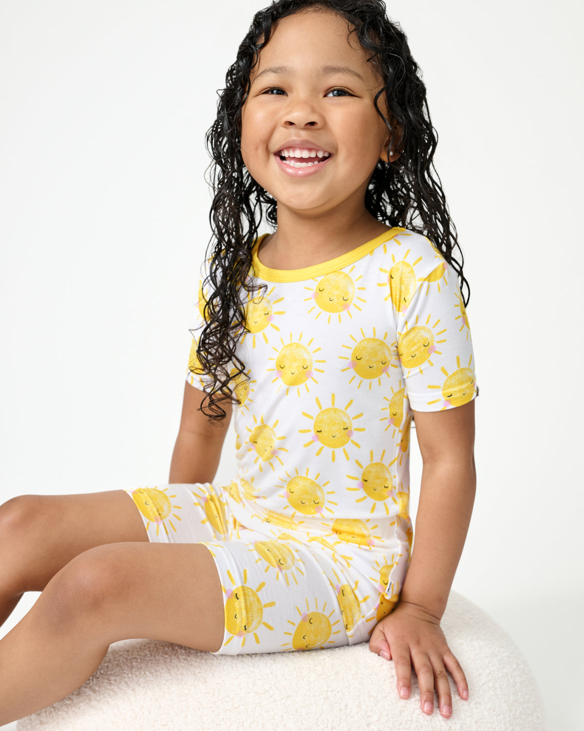 Sitting girl wearing the Sunshine Two-Piece Short Sleeve & Shorts Pajama Set