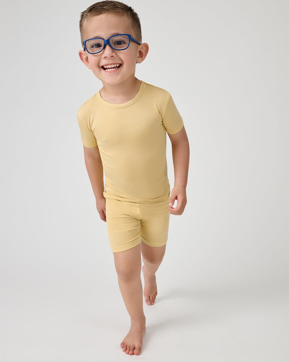 Walking boy wearing the Sunglow Two-Piece Short Sleeve & Shorts Pajama Set