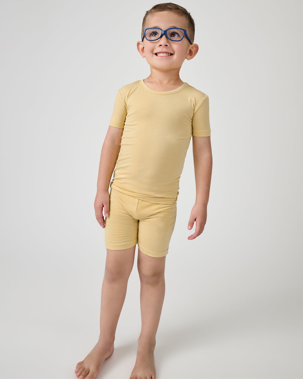 Standing boy wearing the Sunglow Two-Piece Short Sleeve & Shorts Pajama Set