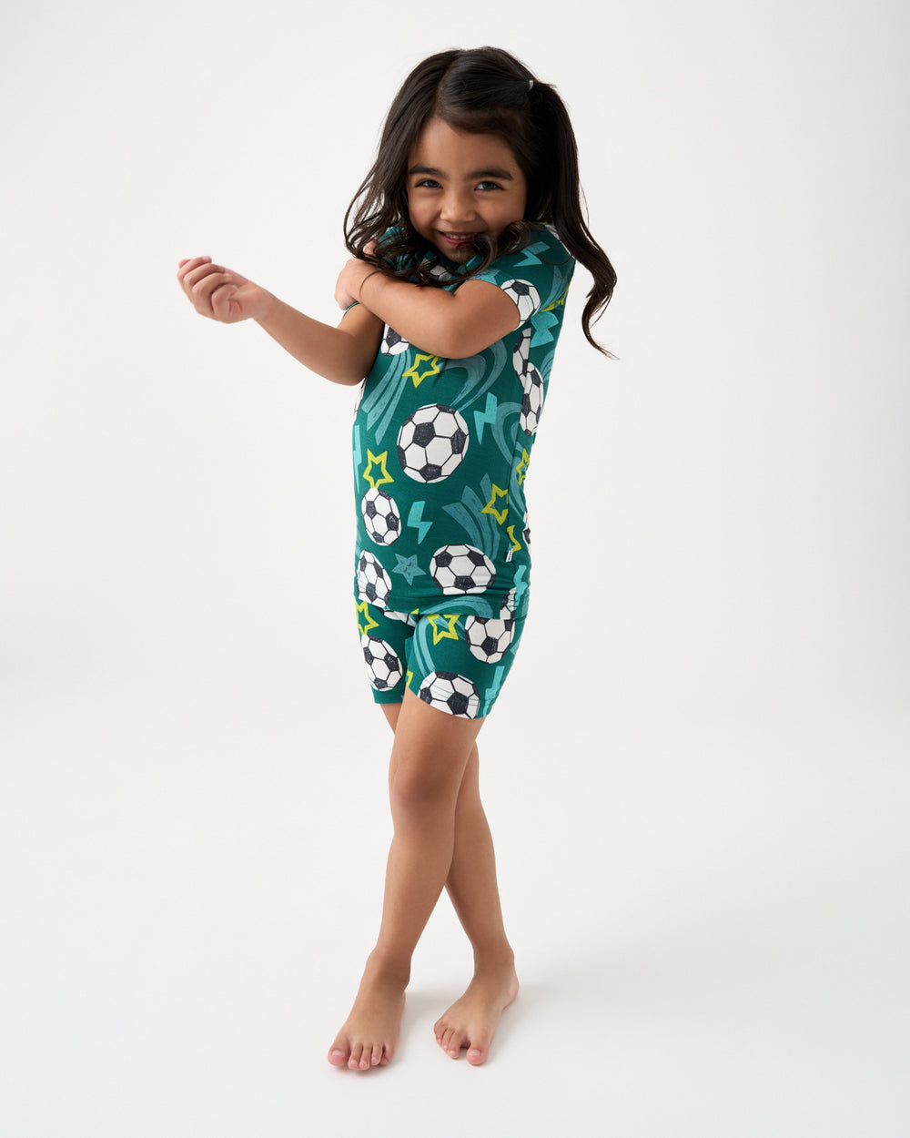 Standing girl wearing the green Soccer Stars Two-Piece Short Sleeve & Shorts Pajama Set