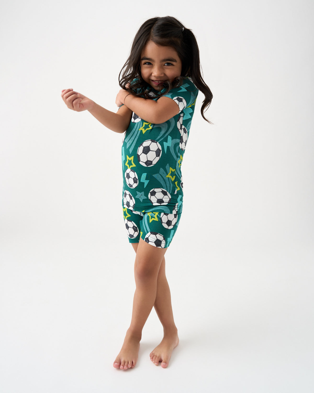 Standing girl wearing the green Soccer Stars Two-Piece Short Sleeve & Shorts Pajama Set