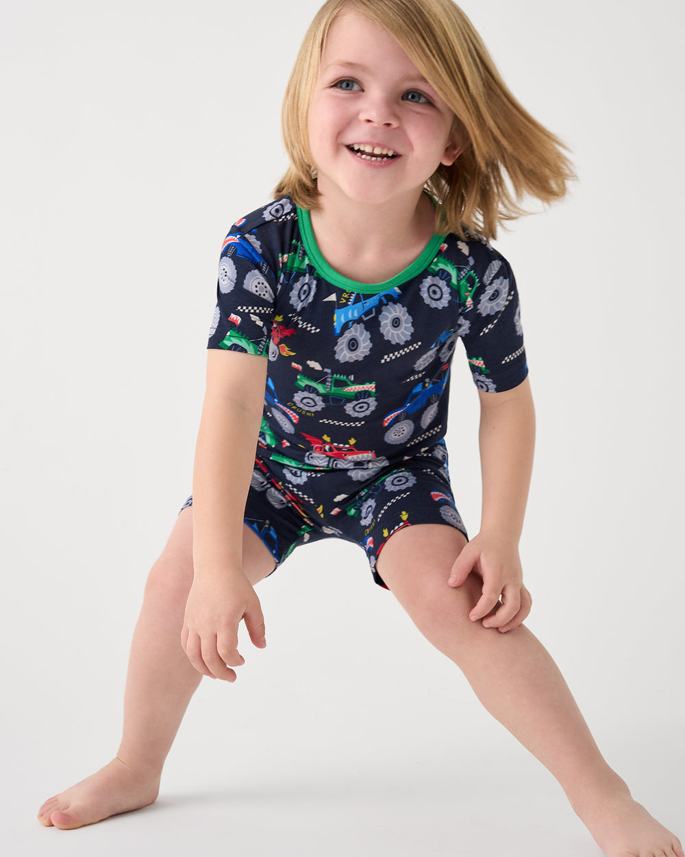 Standing boy wearing the Monster Truck Madness Two-Piece Short Sleeve & Shorts Pajama Set