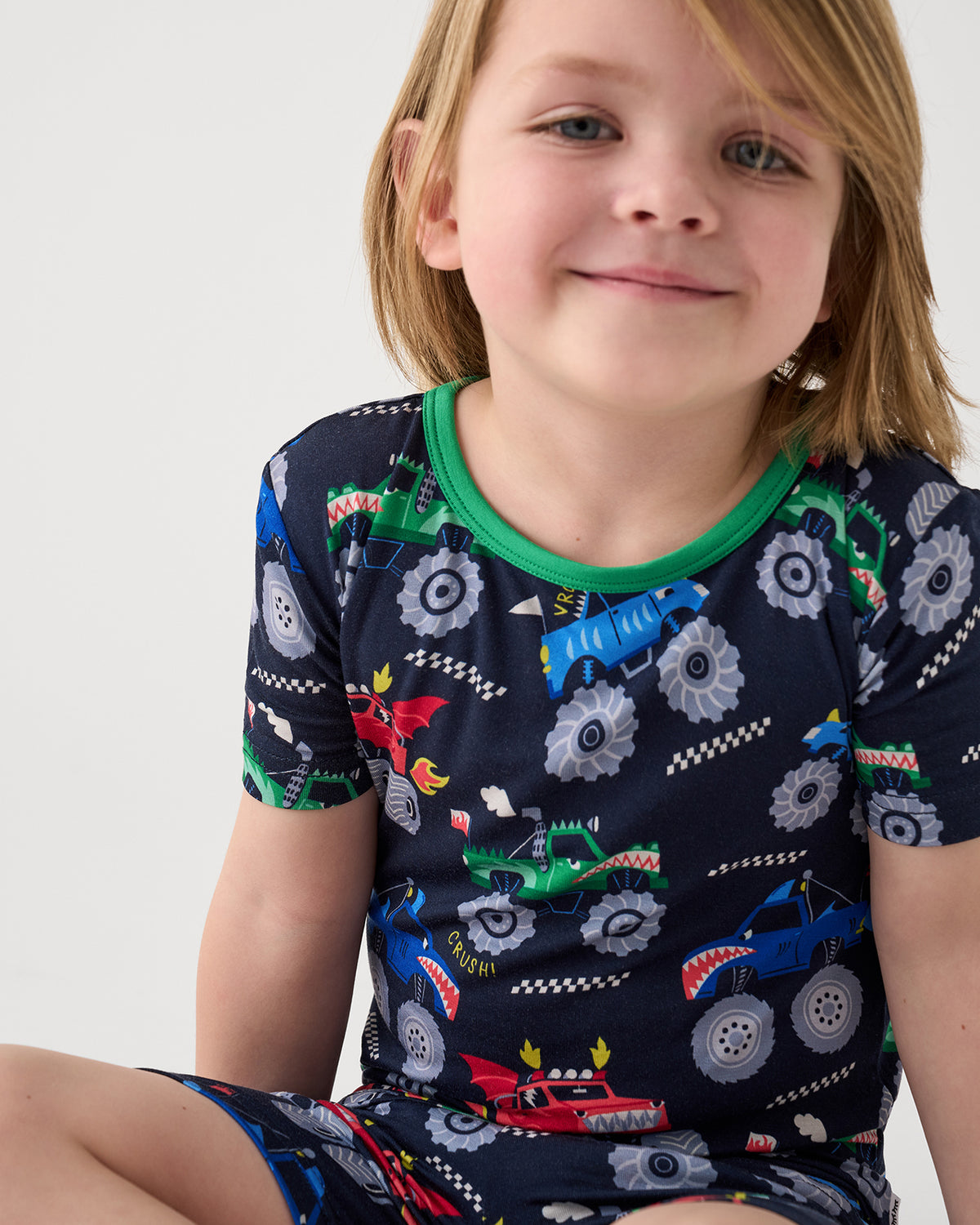Close up of sitting boy wearing the Monster Truck Madness Two-Piece Short Sleeve & Shorts Pajama Set