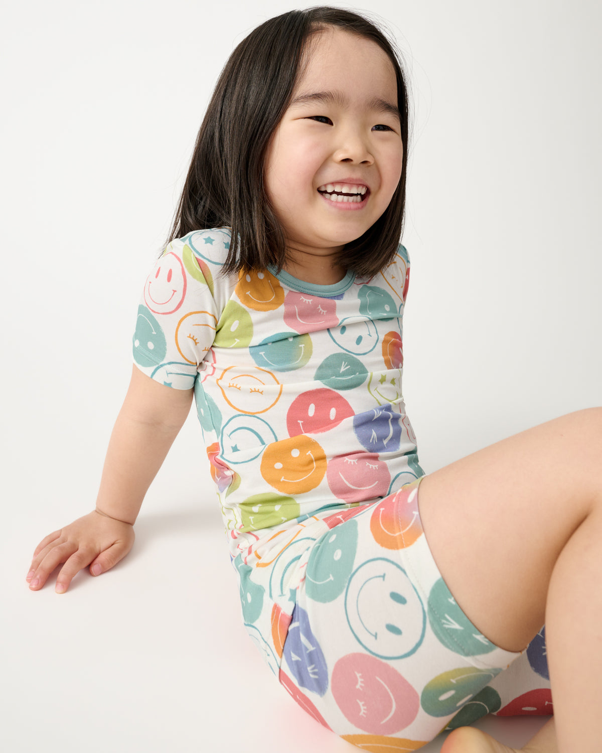 Sitting girl wearing the Positive Vibes Two-Piece Short Sleeve & Shorts Pajama Set