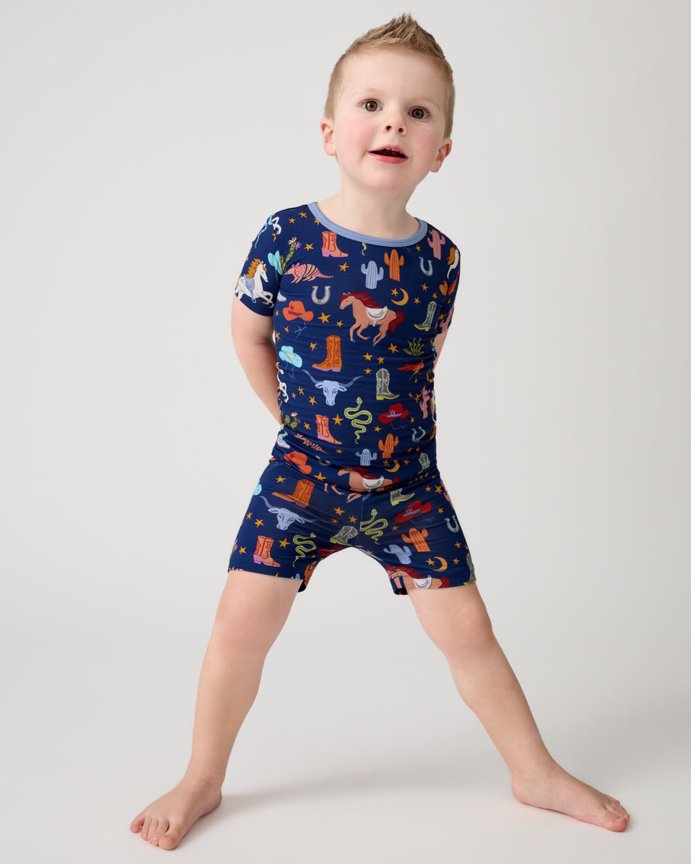 Standing child wearing the Blue Rancher Roundup Two-Piece Short Sleeve & Shorts Pajama Set
