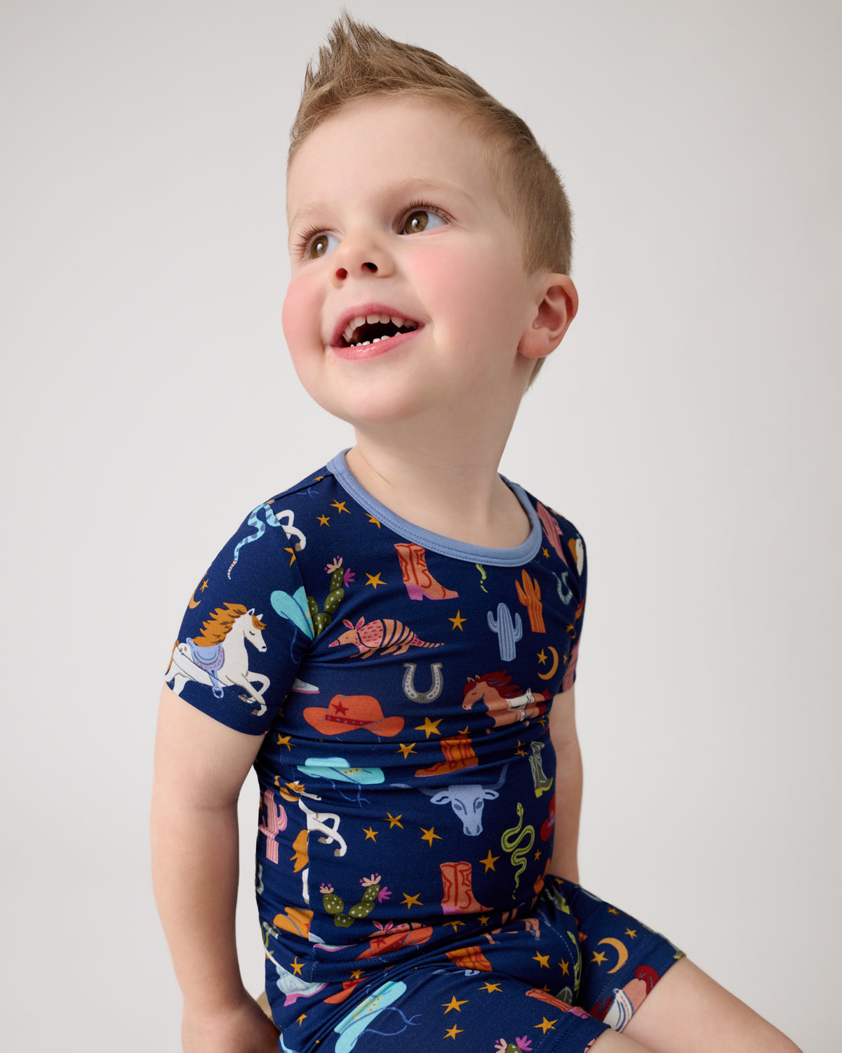 Close up of boy wearing the Blue Rancher Roundup Two-Piece Short Sleeve & Shorts Pajama Set