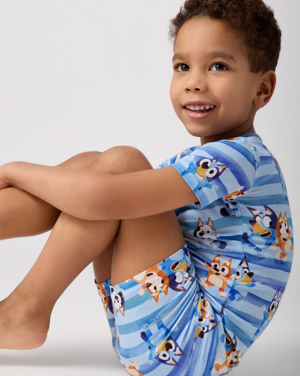Sitting boy wearing the Bluey Dance All Day Two-Piece Short Sleeve & Shorts Pajama Set