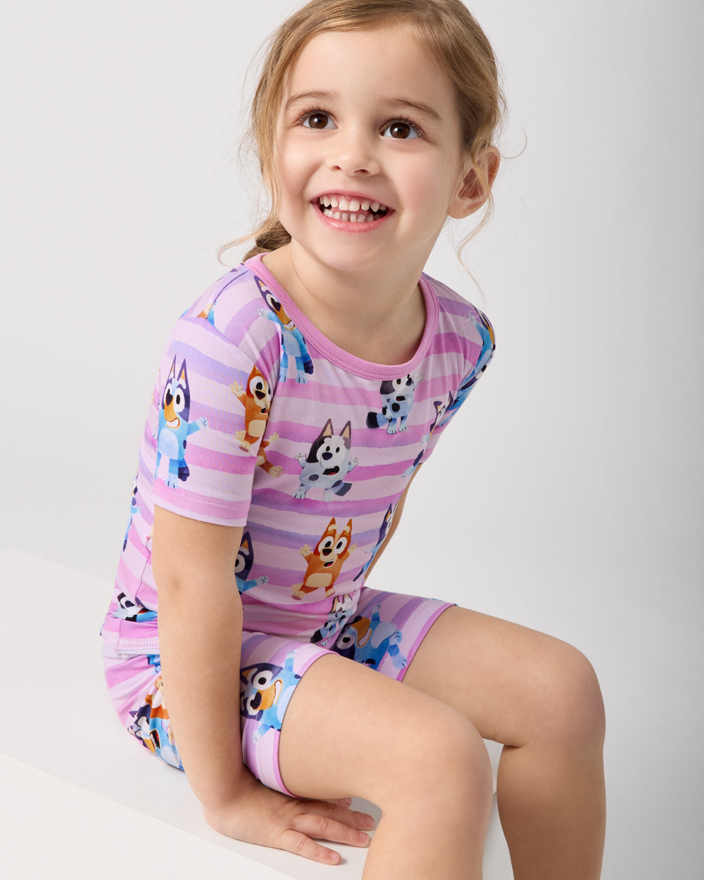 Sitting girl wearing the Pink Bluey Dance All Day Two-Piece Short Sleeve & Shorts Pajama Set