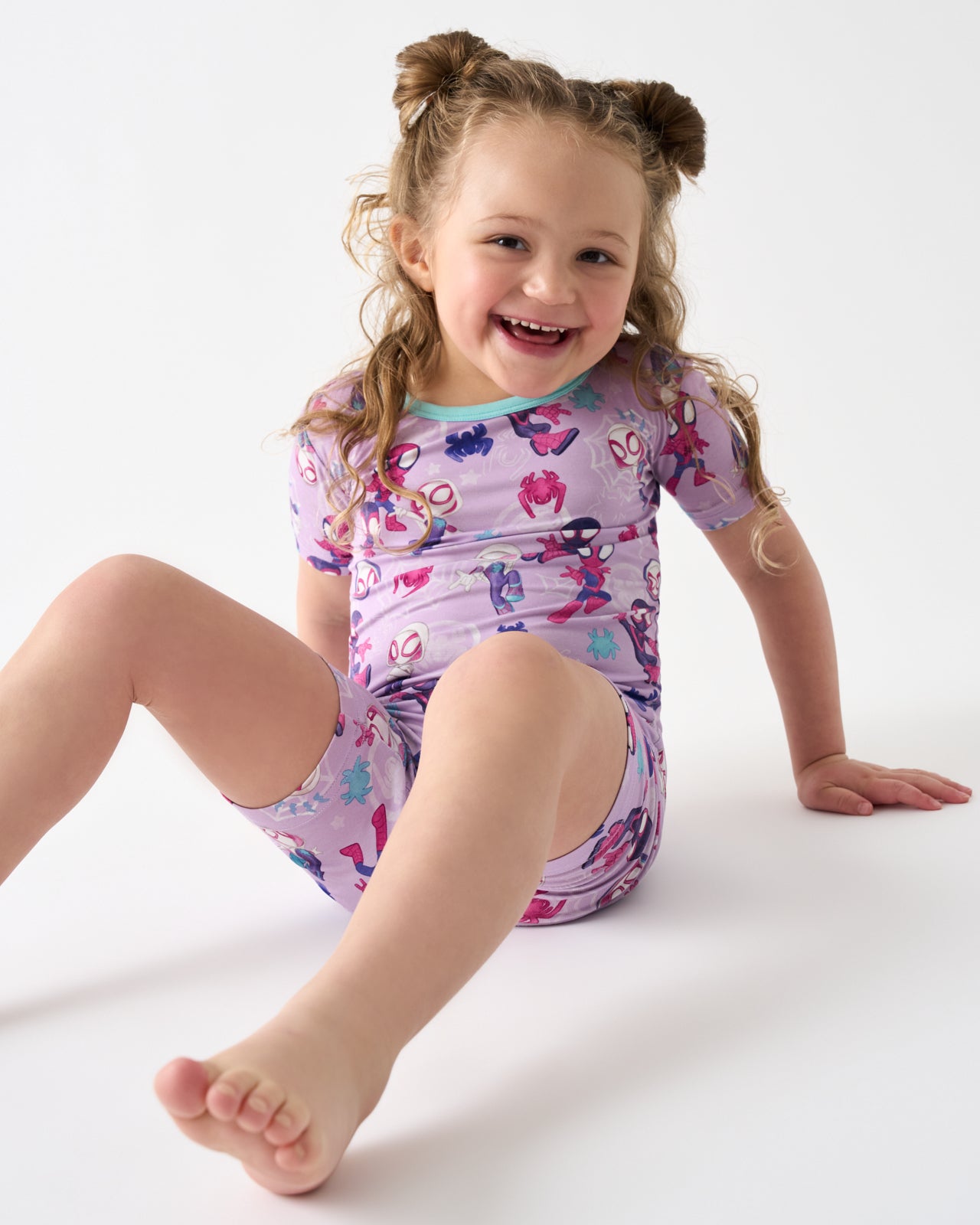 Sitting girl wearing the Spidey & Friends Tiny Webs Two-Piece Short Sleeve & Shorts Pajama Set