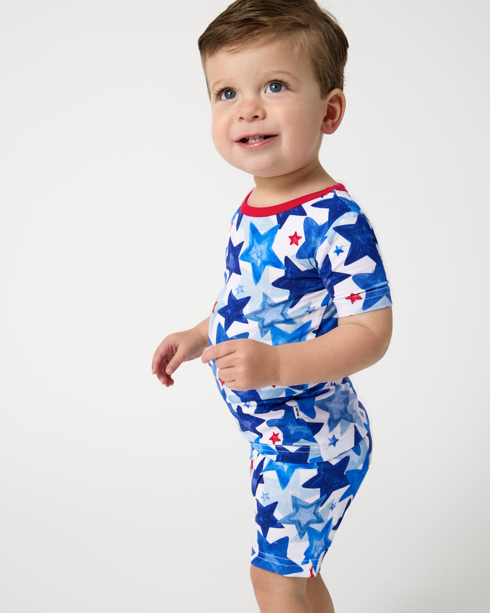 Close up of boy wearing the Starry Splash Two-Piece Short Sleeve & Shorts Pajama Set