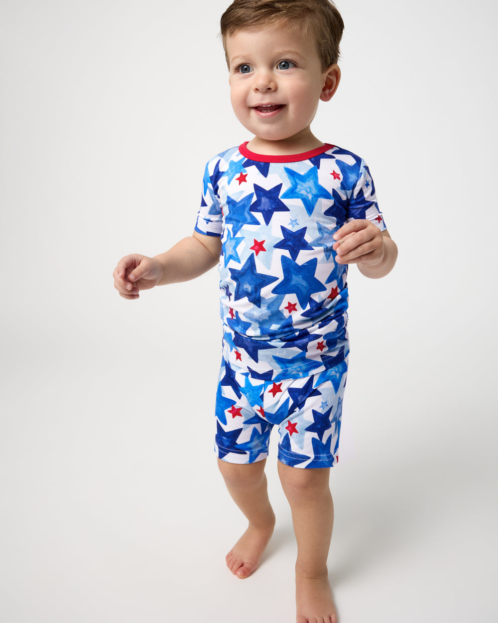 Standing boy wearing the Starry Splash Two-Piece Short Sleeve & Shorts Pajama Set