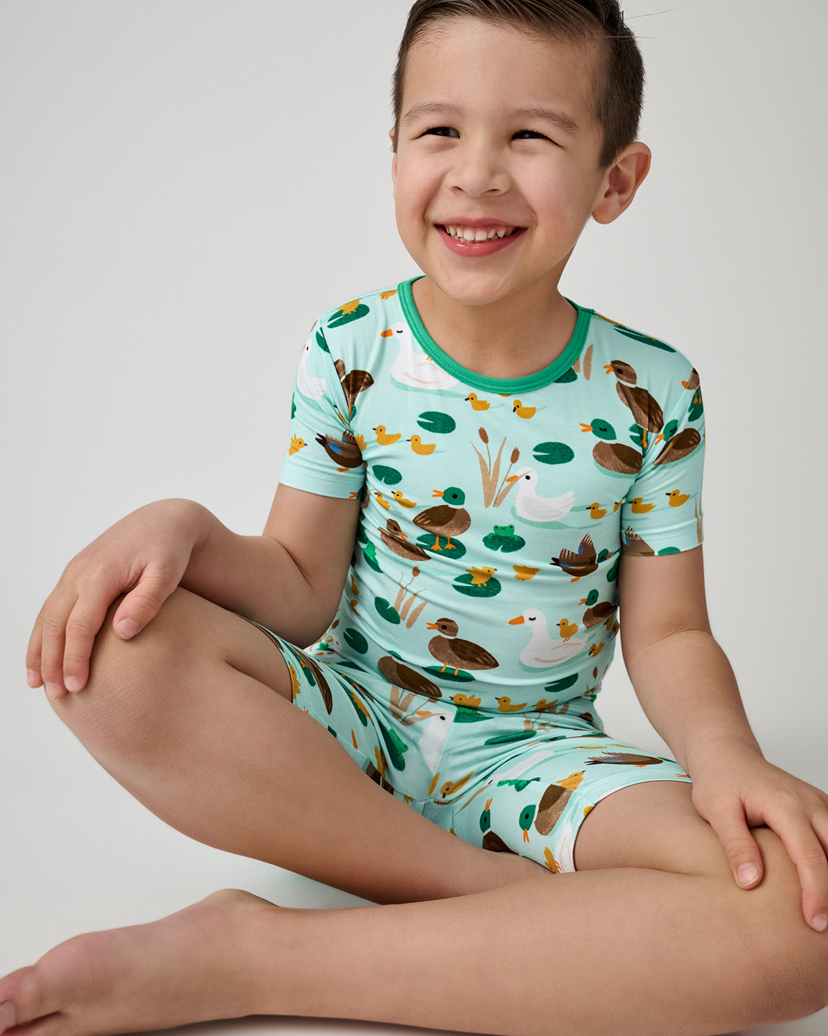 Sitting boy wearing the Puddle Jumpers Two-Piece Short Sleeve & Shorts Pajama Set