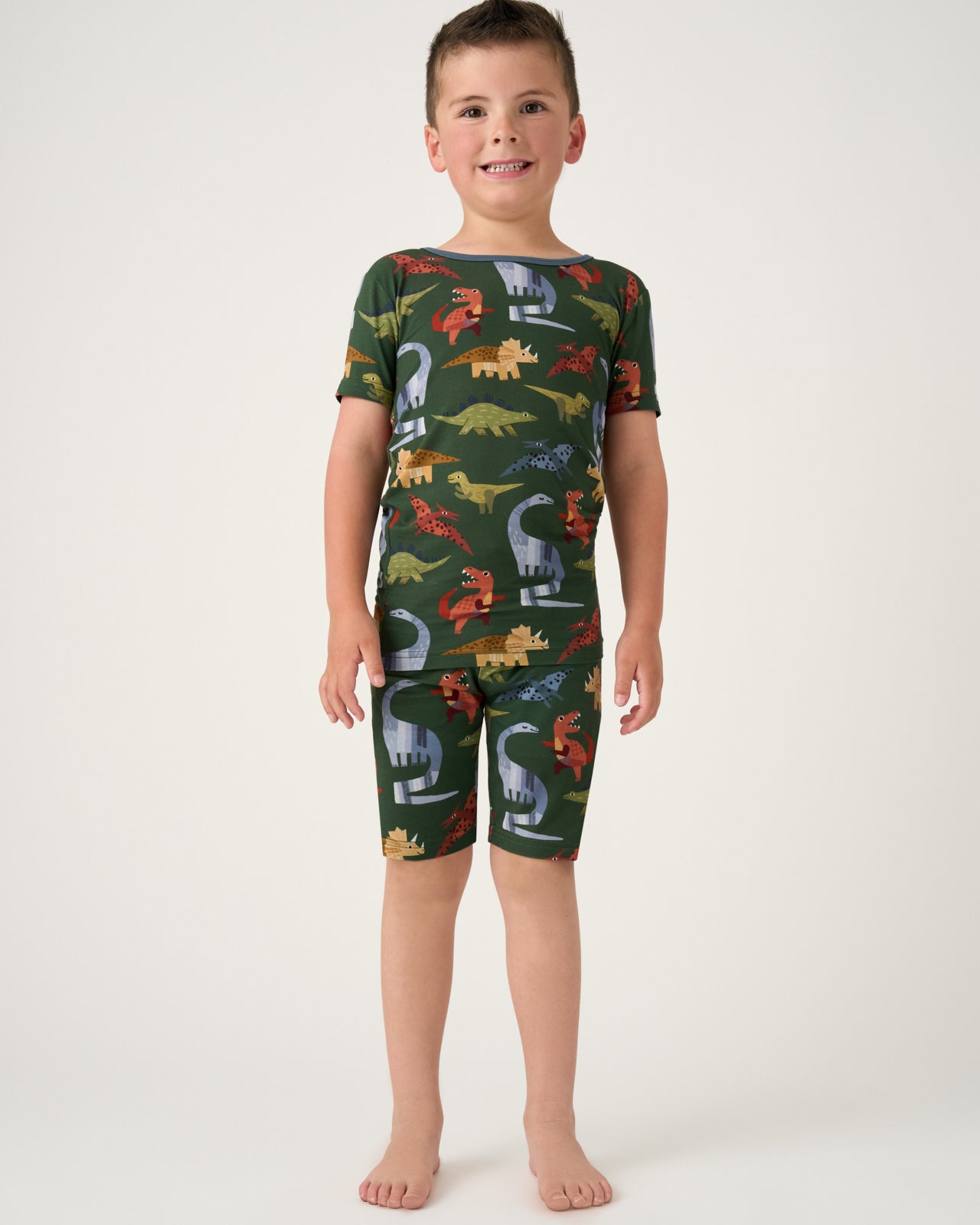 Standing boy wearing the Green Roar & Explore Two-Piece Short Sleeve & Shorts Pajama Set