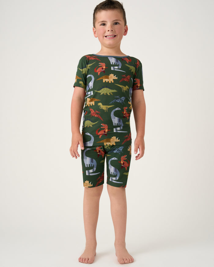 Standing boy wearing the Green Roar & Explore Two-Piece Short Sleeve & Shorts Pajama Set