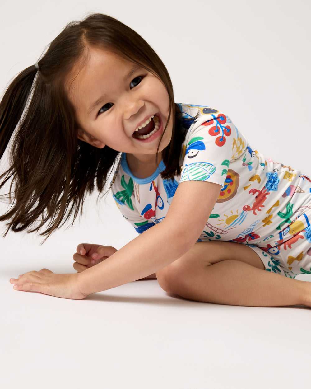 Laughing child wearing the Ciao Bella Two-Piece Short Sleeve & Shorts Pajama Set