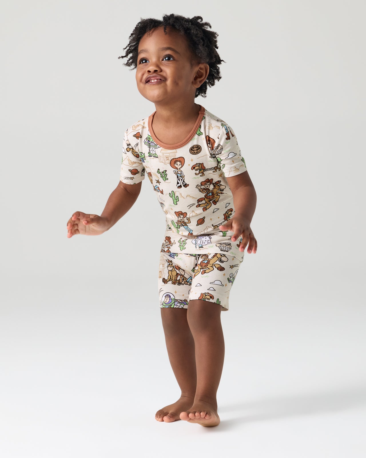 Child wearing the Disney & Pixar Woody's Wild West Two-Piece Short Sleeve & Shorts Pajama Set
