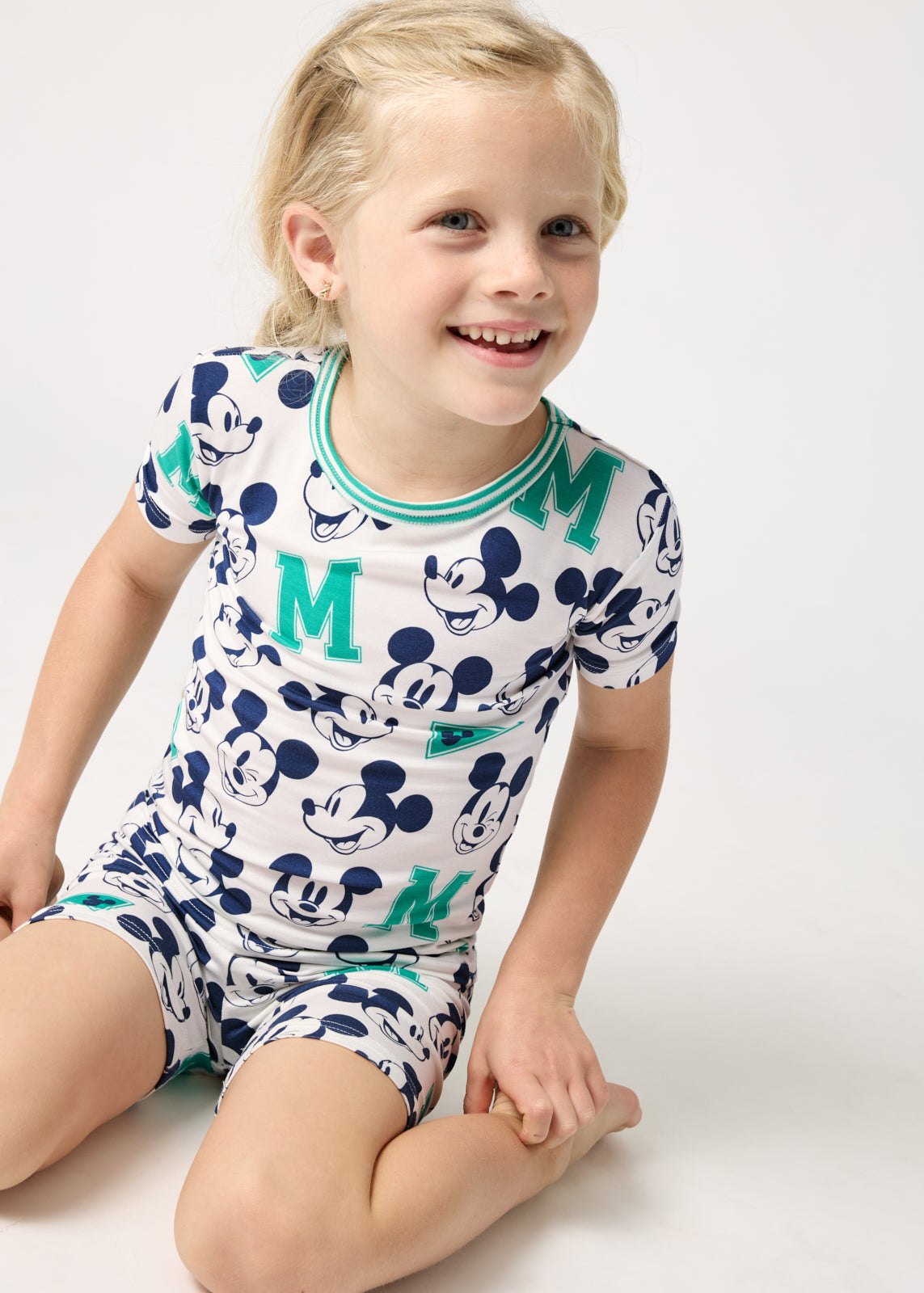 Sitting girl wearing the Disney Varsity Mickey Mouse Two-Piece Short Sleeve & Shorts Pajama Set