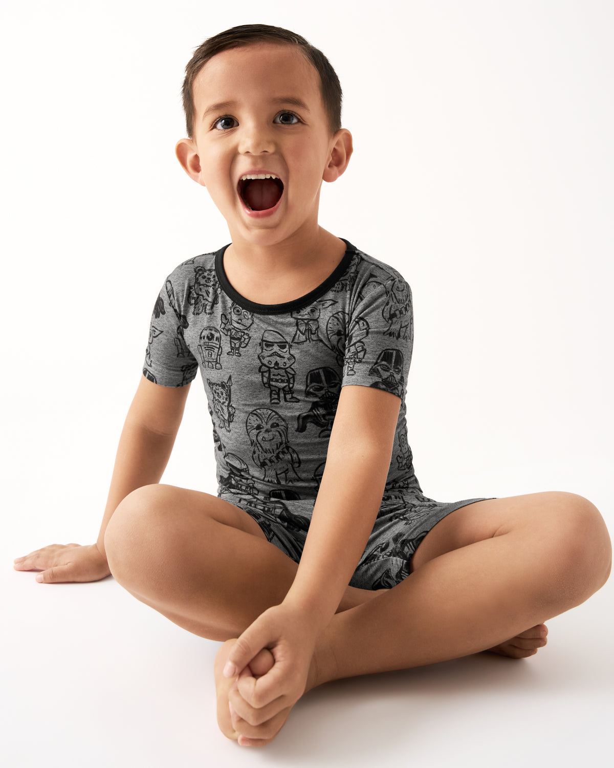 Sitting boy wearing the Star Wars Far, Far, Away Friends Two-Piece Short Sleeve & Shorts Pajama Set