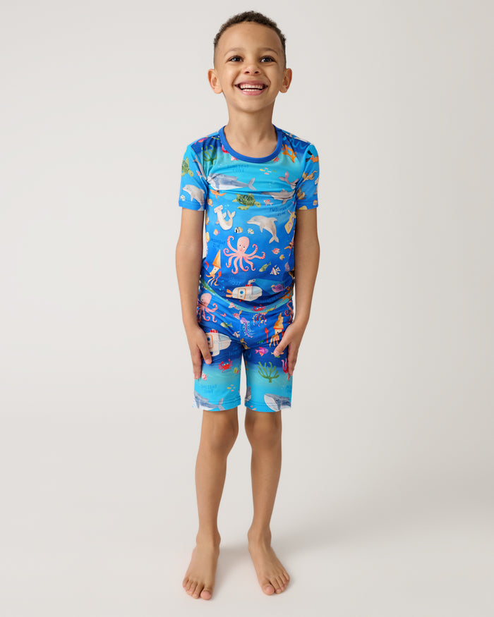 Standing boy wearing the Underwater Discovery Two-Piece Short Sleeve & Shorts Pajama Set