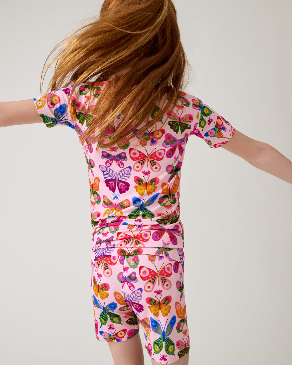 Child in motion wearing the Flutter Garden Two-Piece Short Sleeve & Shorts Pajama Set