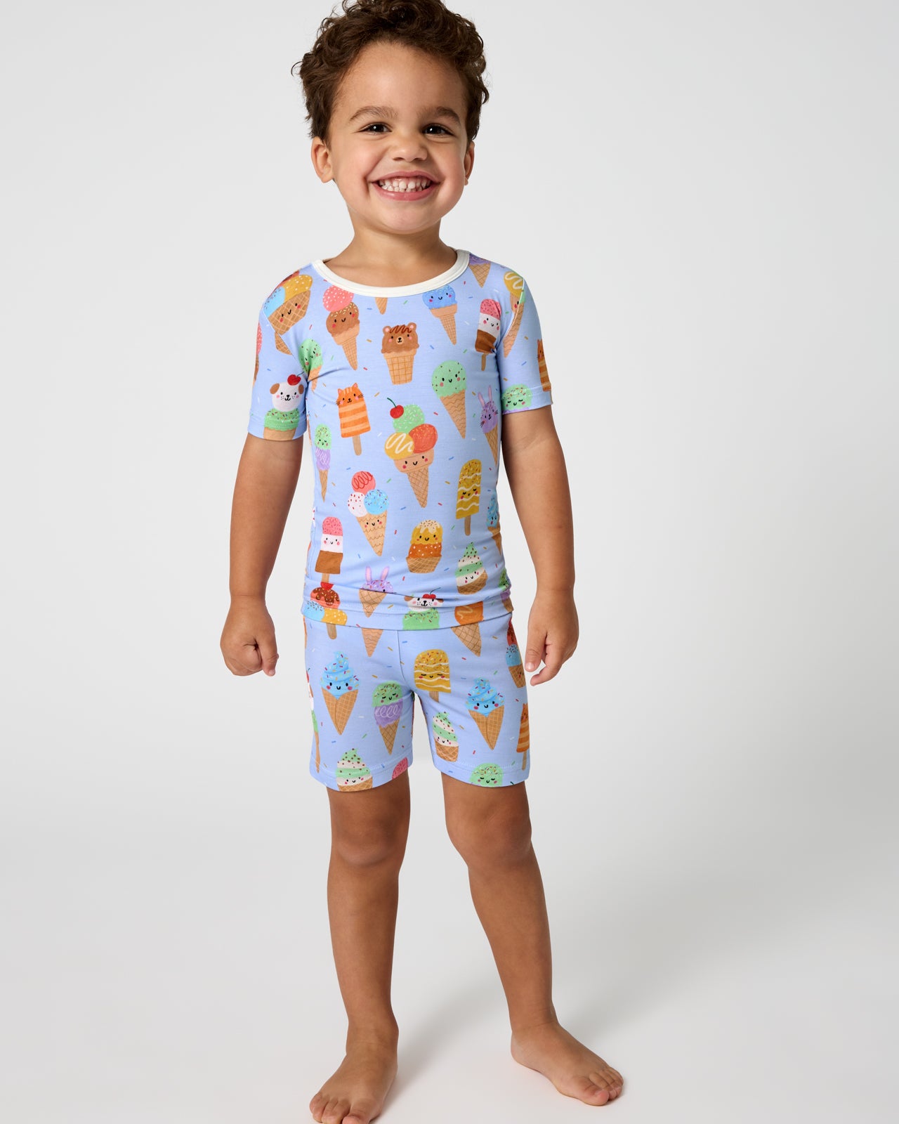Standing boy wearing the Scoop Squad Two-Piece Short Sleeve & Shorts Pajama Set